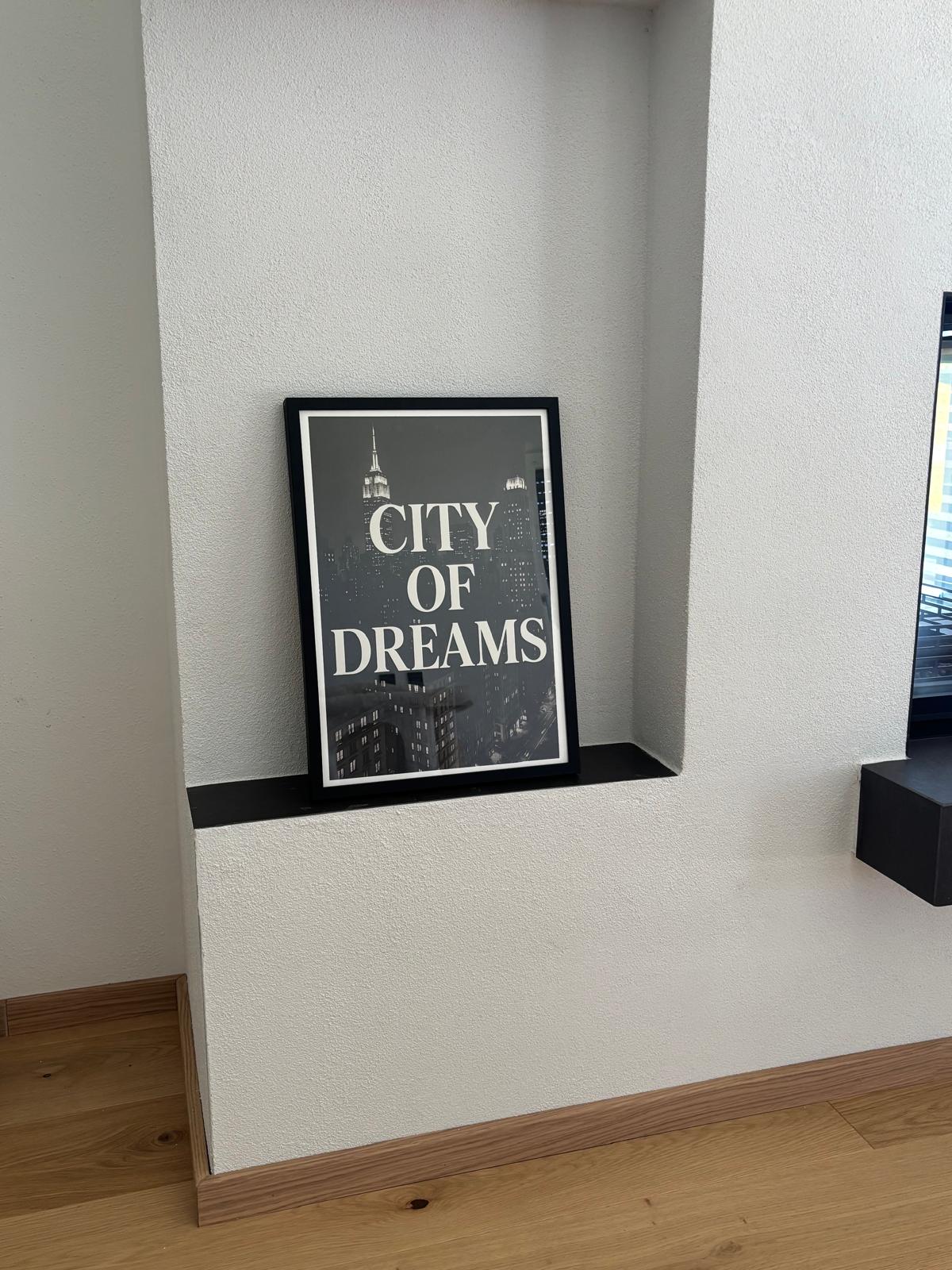City of Dreams typography wall art in a black metal frame displayed on a recessed wall shelf in a customer home
